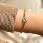 Narukvica – srce (prozirni cirkon) od nehrđajućeg čelika s pozlatom. Elegantan i otporan nakit, savršen za svaki dan. Uskladi s ogrlicom za kompletan look."